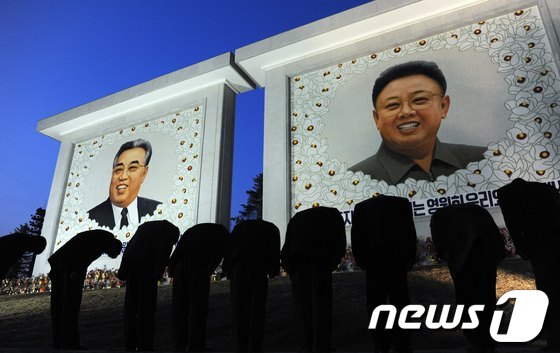 김일성(오른쪽)과 김정일(왼쪽) 초상화에 예를 올리는 북한 주민들