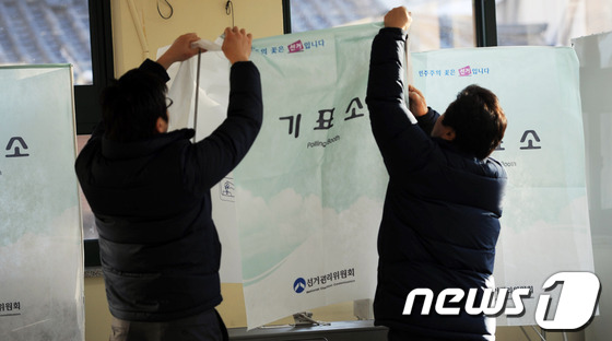 (서울=뉴스1) 이명근 기자 = 제18대 대통령선거를 하루앞둔 18일 오후 서울 종로 교동초등학교에서 종로구 관계자들이 기표소를 설치하고 있다. 2012.12.18/뉴스1