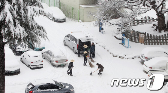 (서울=뉴스1) 김보영  = 대설주의보가 발효된 28일 오전 경남 함양군청에서 밀짚모자를 쓴 공무원들이 주차장에 쌓인 눈을 치우고 있다. (함양군 제공) 2012.12.28/뉴스1 …