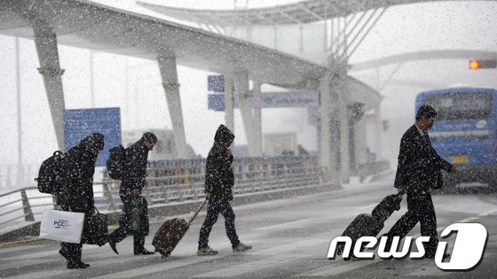 (서울=뉴스1) 이명근 기자 = 때이른 강추위 속에 많은 눈이 내리는 5일 오후 인천국제공항에서 공항이용객들이 눈보라를 헤치며 길을 걷고 있다. 2012.12.5/뉴스1