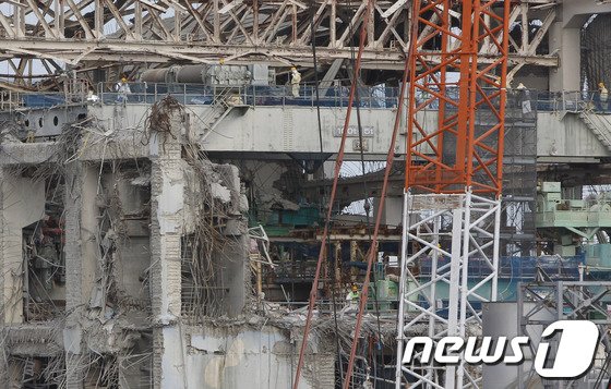 일본 후쿠시마현 제1 원자력발전소 4호기 건물 꼭대기에서 보호복과 마스크를 쓴 직원들이 일하고 있다. 2012.02.20 ⓒAFP=News1