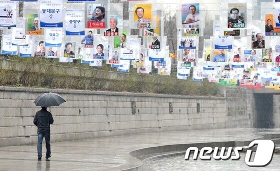 본문 이미지 - 4.11총선을 하루 앞둔 10일 오후 서울 청계천 광통교 인근에서 한 시민이 총선 후보 포스터 아래로 걸어가고 있다. 2012.4.10 /뉴스1 © News1   최진석 인턴기자