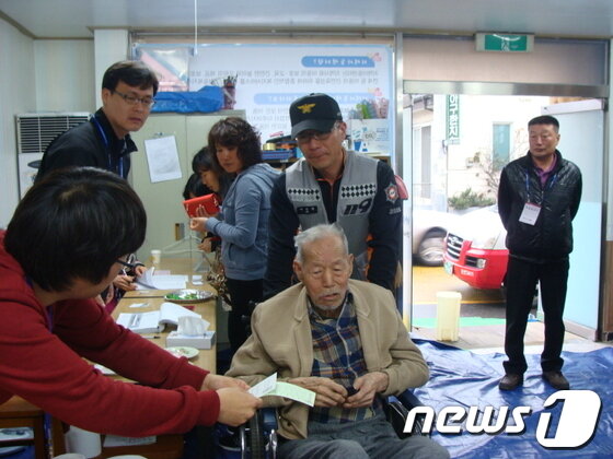 본문 이미지 - 거동이 불편한 윤상보씨가 119구급대의 도움으로 투표에 참여하고 있다. © News1 