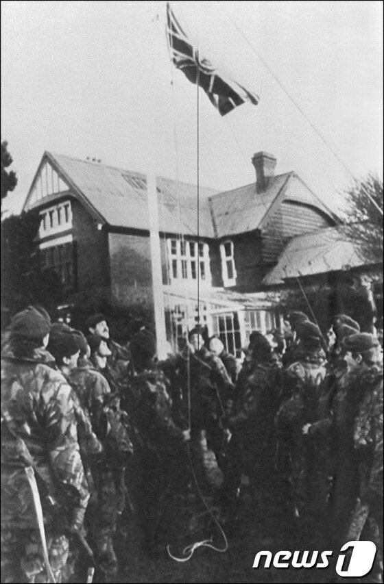 본문 이미지 - 1982년 6월 17일, 아르헨티나의 항복으로 전쟁을 끝낸 영국군들이 유니언잭기를 포클랜드 정부 건물에 걸고 있다.© AFP=News1 