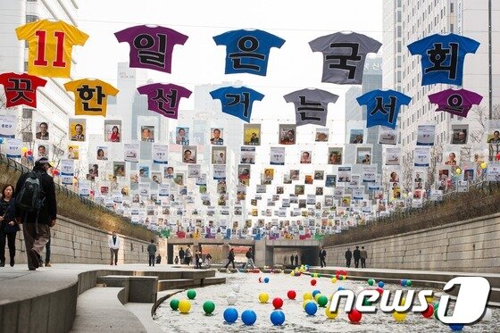 본문 이미지 - 제19대 국회의원선거를 일주일 앞둔 4일 오전 서울 청계천에 투표참여 홍보를 위해 전시된 서울지역에 출마한 174명의 후보자 선거벽보 아래로 시민들이 지나가고 있다. 서울특별시선거관리위원회(위원장 이성보)는 청계천에서 서울지역 모든 후보자의 선거벽보와 특수제작된 티셔츠, 바람개비, 풍선 등을 설치해 유권자의 관심을 유도하고 투표참여 메시지를 전달할 것이라고 밝혔다. © News1 유승관 기자
