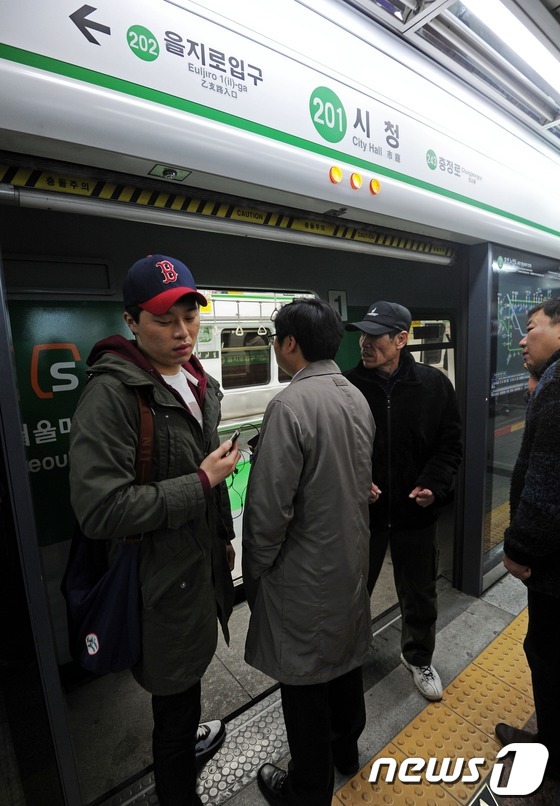 (서울=뉴스1) 오대일 기자 = 강풍으로 전력 공급 전선(전차선)이 늘어지면서 서울 지하철 2호선 운행이 중단된 6일 시청역 열차의 승객들이 멈춰선 열차에서 내리며 관계자에게 항의 …