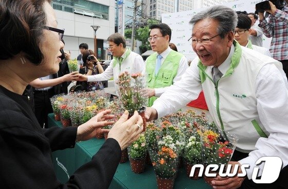 본문 이미지 - 초록우산 어린이재단이 2012년 5월 24일 오전 서울 무교동 재단빌딩 앞에서 한국농수산식품유통공사와 함께 상호 간의 직거래장터 협약을 기념해 시민들에게 화분을 나누어주고 있다. 2012.5.24/ 뉴스1