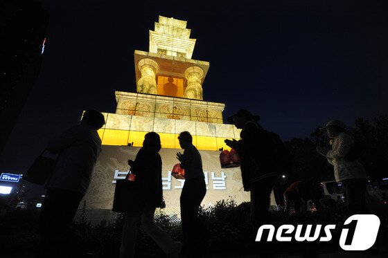 본문 이미지 - 부처님오신날을 앞두고 7일 저녁 서울 중구 태평로 서울광장에서 열린 '봉축장엄등 점등식'에서 불자들이 탑돌이를 하고 있다. 올해 서울광장에 불을 밝힌 봉축등은 국보 제35호 구례 화엄사 사사자삼층석탑을 원형으로 삼아 전통한지로 제작됐다. 2012.5.7/뉴스1 © News1   박지혜 기자