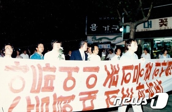 본문 이미지 - 6 월 항쟁 당시 중구 성남동 부근에서 울산국본 시위대가 현수막을 들고 가두행진을 벌이고 있다. 가운데 양복입은 사람이 김위경 당시 통일민주당 경남제2지구당 조직부장이다./사진제공=김위경 (사)아시아태평양환경NGO한국본부 회장 © News1 