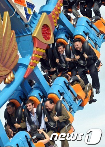 본문 이미지 - 지난 7월 25일 평양 릉라인민유원지에서 놀이기구를 타는 김정은 북한 국방위원회 제1위원장의 모습. 앞줄 가운데 앉은 사람이 바나비 존스 북한 주재 영국 대사관 1등 서기관이다. ⓒAFP=News1