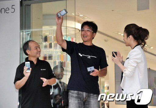 본문 이미지 - 21일 도쿄에서 아이폰5를 처음으로 구입한 고객(중간)이 손정의 소프트뱅크 회장(왼쪽)과 일본 여배우 우에토 아야를 옆에 두고 아이폰5를 번쩍 들어 보여주고 있다. © AFP=News1 
