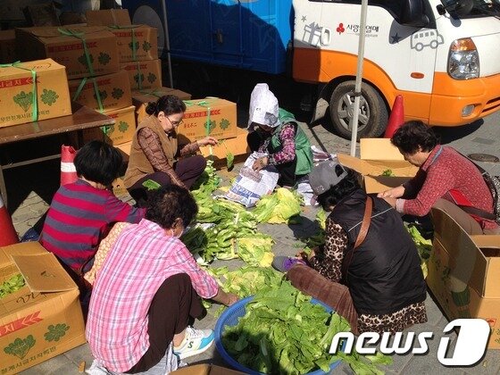 본문 이미지 - 지구촌사랑나눔 건물 앞 천막에서 쉼터 이용자들이 가락시장에서 무료로 받은 채소를 다듬고 있다. © News1 