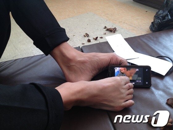 본문 이미지 - 지구촌사랑나눔에는 몸이 불편한 중국 교포 등 50여명이 거주하고 있다. 양팔이 없는 최금호씨가 발로 스마트폰을 조작해 영상을 보여주고 있다. © News1 