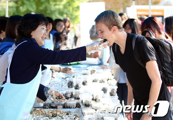 (서울=뉴스1) = 21일 오후 숙명여대 순헌관 앞 광장에서 열린 중간고사 간식배부 행사에서 황선혜 숙명여대 총장과 교무위원들이 직접 만든 주먹밥을 학생들에게 먹여주고 있다. (숙 …