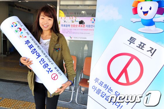 본문 이미지 - 10.30포항남ㆍ울릉 재선거 사전투표가 시작된 25일 남구 연일읍 사무소에서 투표를 마친 여성 유권자가 &#39;투표인증 포토존에서&#39; 인증사진을 찍고 있다. 선관위는 투표를 마친 유권자들이 손가락 등으로 특정 기호를 나타내는 것을 예방하기 위해 도장 모양의 기념물로 사진촬영을 할 수 있도록 유도하고 있다.2013.10.25/뉴스1 © News1   최창호 기자