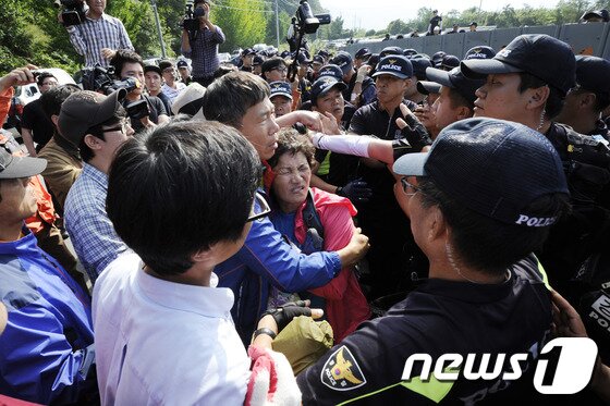 본문 이미지 - 밀양 송전탑 공사재개 이틀째인 3일 오후 밀양 단장면 단장리 765㎸ 신고리-북경남 송전선로 건설공사 4공구 현장사무소 앞에서 송전탑 반대 주민들과 집회 참가자들이 경찰과 몸싸움을 벌이고 있다. 2013.10.3/뉴스1 © News1 전혜원 기자