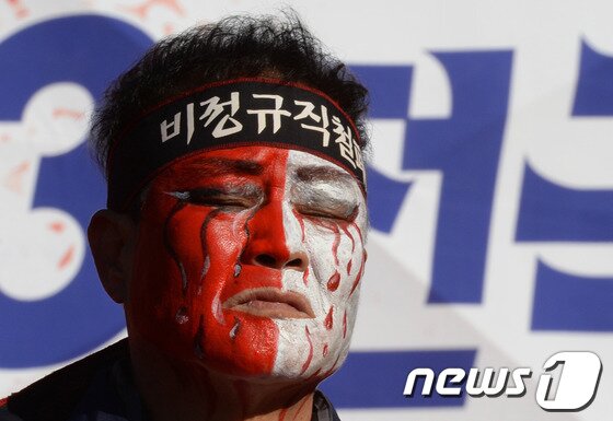 본문 이미지 - 전국민주노동조합총연맹(민주노총)이 10일 오후 서울광장에서 개최한 전국노동자대회에서 한 참가자가 연단에 올라 지난달 스스로 목숨을 끊은 삼성전자서비스 천안서비스센터 직원 최종범(32)씨의 영정사진을 들고 있다.. 2013.11.10/뉴스1 © News1 정회성 기자