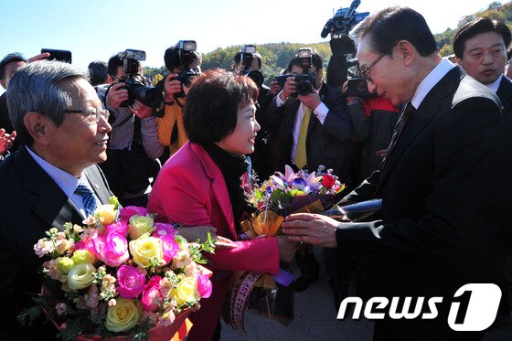 본문 이미지 - 고향마을인 북구 흥해읍 덕실마을을 찾은 이 대통령 내외가 오찬장 앞에서 고향마을 주민들로부터 꽃다발을 받고 있다.2013.11.13/뉴스1 © News1   최창호 기자