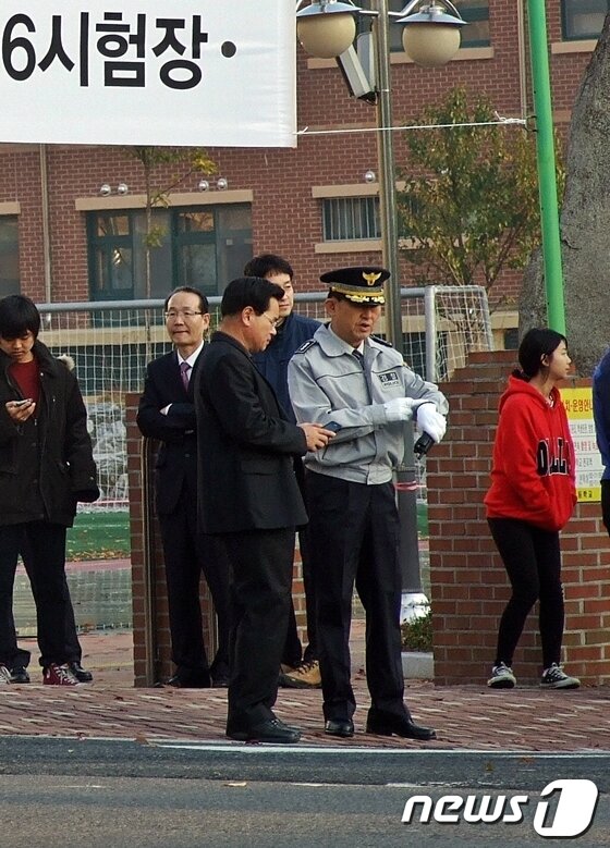 본문 이미지 - 2014학년도 대입수학능력시험이 7일 오전 일제히 시작한 가운데 곽생근 울산울주경찰서장(왼쪽, 검은 옷)이 울산 울주군 범서고 앞에서 시험장 주변을 관리하던 중 입실 종료 시간이 다가오자 스마트폰으로 시간을 확인하고 있다. © News1 김규신 기자  