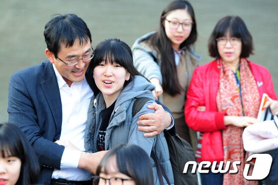 본문 이미지 - 2014학년도 대학수학능력시험일인 7일 오후 경북 포항시 유성여고에서 시험을 마친 한 수험생들이 교문밖에서 기다리고 있던 아버지에게 달려가 안기고 있다.2014.11.7/뉴스1 © News1   최창호 기자
