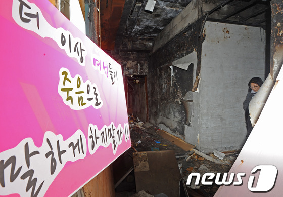 (전주=뉴스1) 김대웅 기자 = 전북 군산 개복동 성매매 업소 화재 참사 현장 철거를 하루 앞둔 25일 여성 단체회원들이 11년동안 막아두었던 화재 현장을 둘러 보고 있다.군산 개 …