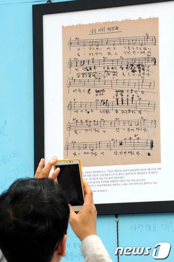 (서울=뉴스1) 안은나 기자 = 5·18민주화운동 제33주년 기념일인 18일 오전 서울광장에서 한 시민이 '님을 위한 행진곡' 악보의 사진을 스마트폰으로 촬영하고 있다. 2013. …