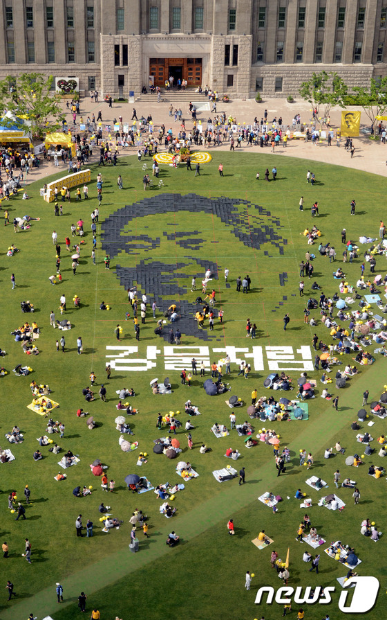 (서울=뉴스1) 박세연 기자 = 노무현 4주기 추모문화제가 열린 19일 오후 시민들이 종이를 이어붙여 서울광장에 노무현 전 대통령의 얼굴을 만들고 있다.2013.5.19/뉴스1