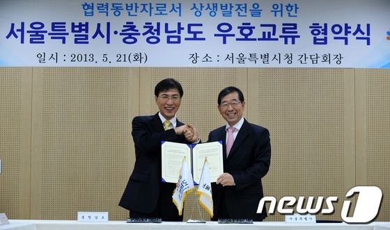 (서울=뉴스1)  = 박원순 서울시장과 안희정 충남도지사가 21일 서울시청에서 열린 '서울시-충청남도 우호교류 협약식'에서 협약서에 서명을 한 후 악수하고 있다. (서울시 제공) …