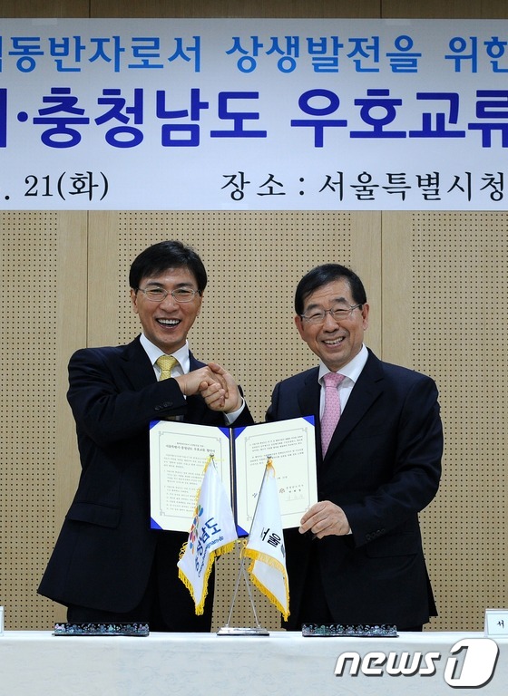 (서울=뉴스1)  = 박원순 서울시장과 안희정 충남도지사가 21일 서울시청에서 열린 '서울시-충청남도 우호교류 협약식'에서 협약서에 서명을 한 후 악수하고 있다. (서울시 제공) …