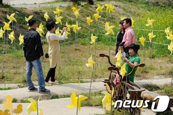 본문 이미지 - 고 노무현 전 대통령 4주기를 하루 앞둔 22일 오후 김해 봉하마을에 설치된 노란 바람개비 앞에서 추모객들이 사진을 찍고 있다. 2013.5.22/뉴스1 © News1 전혜원 기자
