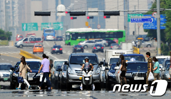 (서울=뉴스1) 양동욱 기자 = 서울의 낮 최고기온이 30도까지 오르며 올들어 가장 더운 날씨를 보인 23일 서울 여의대로 횡단보도에서 아스팔트의 아지랑이 사이로 시민들이 발걸음을 …