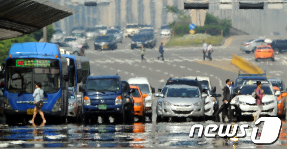 (서울=뉴스1) 양동욱 기자 = 서울의 낮 최고기온이 30도까지 오르며 올들어 가장 더운 날씨를 보인 23일 서울 여의대로 횡단보도에서 시민들이 아스팔트의 아지랑이 사이로 발걸음을 …