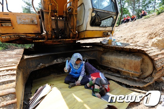 (밀양=뉴스1) 전혜원 기자 = 한전이 밀양지역 765kV 송전탑 공사를 닷새째 이어간 24일 오전 밀양 단장면 바드리 송전탑 공사현장에서 주민들이 굴착기 그늘 아래에서 시위를 벌 …