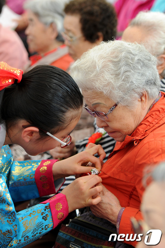 (서울=뉴스1) 안은나 기자 = 어버이날인 8일 서울 송파구 서울놀이마당에서 열린 제41회 어버이날 행사에서 어린이들이 어르신들에게 카네이션을 달아드리고 있다. 2013.5.8/뉴 …