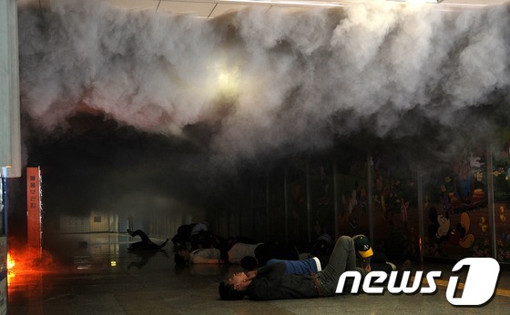 (서울=뉴스1) 양태훈 인턴기자 = 재난대응 안전한국훈련의 일환으로 '생화학테러 대비 통합훈련'이 실시된 8일 오후 서울 용산구 삼각지역 대합실에서 시민들이 화학물질을 마시고 괴로 …