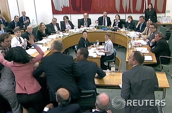 본문 이미지 - 청문회 당시 한 남성이 머독에게 면도크림을 던지려는 순간 덩이 그를 저지하는 모습. © 로이터=News1  