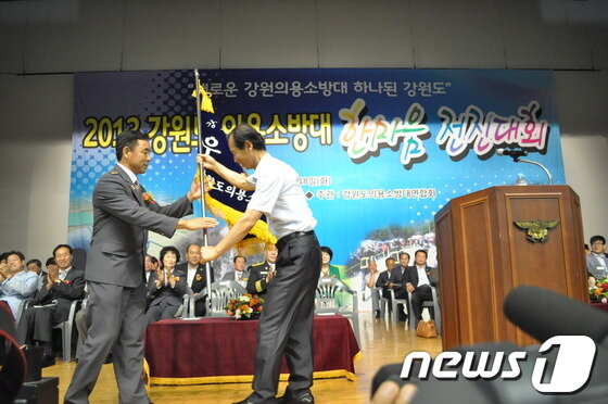 본문 이미지 - 18일 오전 호반체육관에서 열린 2013 의용 소방대 한마음 전진대회에서 최문순 도지사가 민경식 의용소방대연합회장에게 우승기를 전달하고 있다© News1 홍성우 기자 