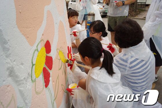 본문 이미지 - 벽화그리기에 동참한 학부모와 학생들이 학교담당에 꽃을 그리고있다. 2013.6.20/뉴스1 © News1 이예지 기자 