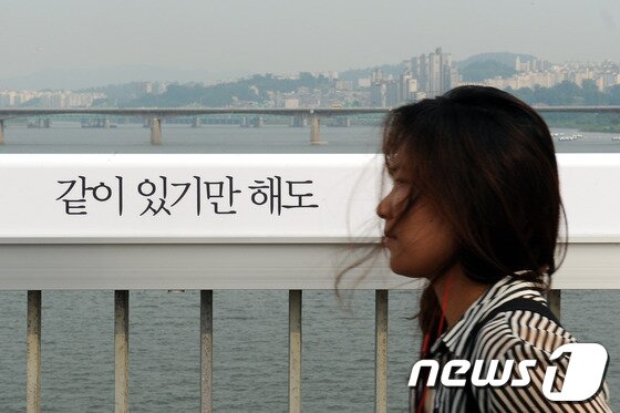 본문 이미지 - 투신자살의 명소라는 악명을 가진 서울 영등포구 마포대교가 시민공모를 통해 선정된 문구로 새로 단장하고 &#39;생명의 다리&#39;로 탈바꿈했다. 한 시민이 마포대교에 설치된 문구를 보고지나가는 시민. © News1   양태훈 인턴기자