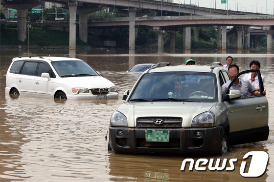 (서울=뉴스1) 이광호 기자 = 서울을 비롯한 경기 남부 지역에 시간당 30mm가 넘는 장대비가 쏟아진 22일 오후 서울 송파구 탄천주차장에서 관계자들이 침수된 차량을 밀고 있다. …