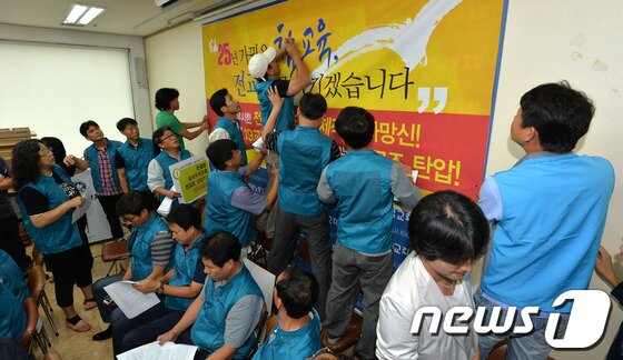 본문 이미지 - 24일 서울 영등포구 전국교직원노동조합 회의실에서 열린 민주주의 말살-전교조 탄압 규탄 및 총력투쟁 선포 전교조 기자회견 전 관계자들이 현수막을 붙이고 있다. 고용노동부는 23일 전교조가 다음달 23일까지 해직자의 노조 가입을 허용하는 규약을 시정하지 않을 경우 법외노조가 된다는 내용의 공문을 보냈다. 2013.9.24/뉴스1