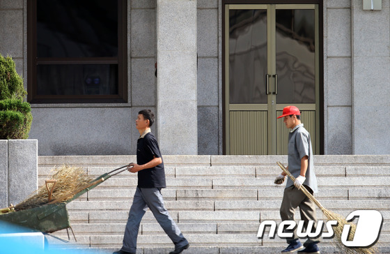 (판문점=뉴스1) 한재호 기자 = 25일 오전 판문점에서 북측 지역인 판문각 앞을 작업 인부들이 지나고 있다. 인부들이 지나가자 남측을 주시하던 북한군 병사가 기둥 뒤로 몸을 숨기 …