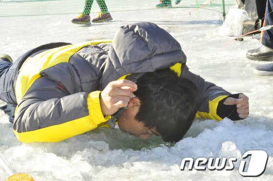 본문 이미지 - 주말인 11일 화천 산천어 축제에 찾은 한 관광객이 엎드려서 낚시를 하고 있다.2013.01.11/뉴스1 © News1   홍성우 기자