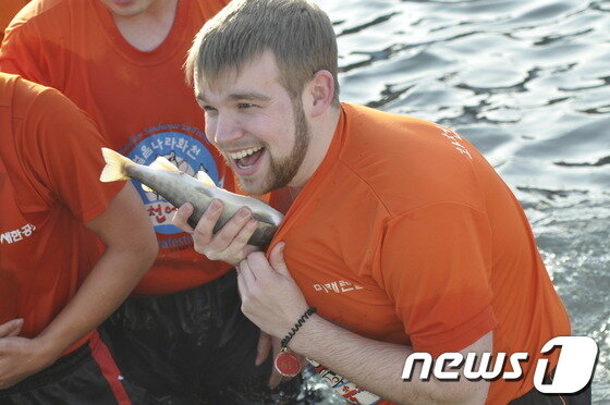 본문 이미지 - 화천 산천어 축제가 열리고 있는 가운데 11일 '맨손잡기 체험'에 참가한 외국인이 잡은 산천어를 옷속에 넣으며 기뻐하고 있다.2014.01.11/뉴스1 © News1   홍성우 기자