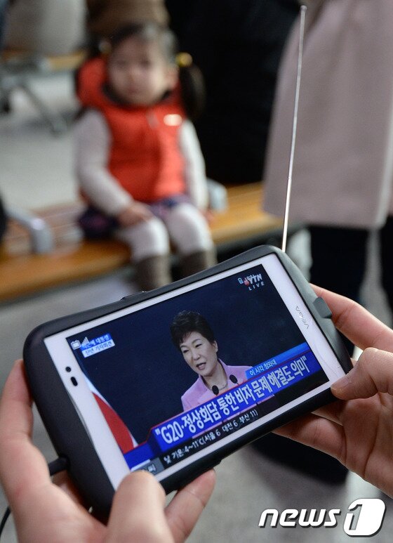 본문 이미지 - 6일 오전 서울 용산구 서울역 대합실에서 한 시민이 박근혜 대통령의 첫 신년 기자회견 생중계를 스마트폰으로 지켜보고 있다. 이날 박 대통령은 기자회견을 통해 