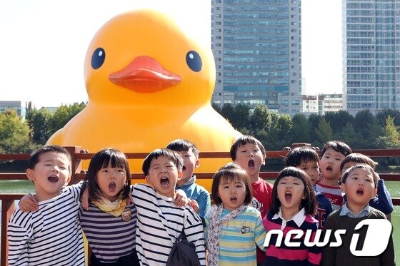 본문 이미지 - 14일 서울 송파구 석촌호수를 찾은 어린이들이 대형 고무 오리 '러버덕(Rubber Duck)'을 배경을 사진을 찍고 있다. 2014.10.14/뉴스1 ⓒ News1 한재호 기자