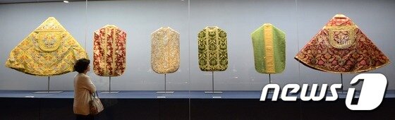 본문 이미지 - 프란치스코 교황 방한기념특별전 '천국의문' 전시회을 찾은 관람객이 16~18세기 바티칸에서 사용한 전례용 제의 등을 살펴보고 있다. 2014.10.19/뉴스1 ⓒ News1 정회성 기자