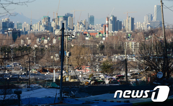 (서울=뉴스1) 한재호 기자 = 18일 서울 시내 최대 규모의 무허가 판자촌인 구룡마을 너머로 강남의 고층 빌딩숲이 보이고 있다.이날 서울시는 그동안 강남구와 갈등으로 무산됐던 강 …
