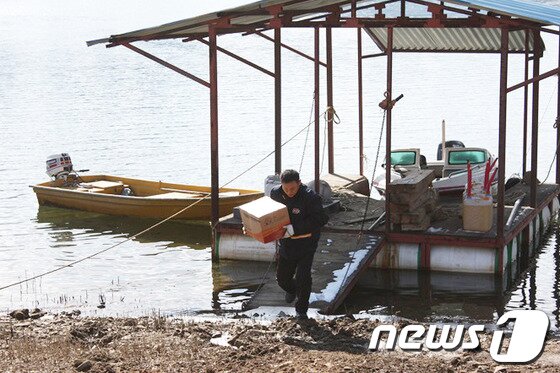 본문 이미지 - &#39;육지속의 섬&#39;이라고 불리는 양구 상무룡리를 가려면 차로호 월명리 선착장에서 배를 타고 들어가야 한다. 양구우체국 김동훈 집배원이 우편물 배달을 위해 배에서 내리고 있다.&#40;강원지방우정청 제공&#41;.2014.2.21/뉴스1 © News1   권혜민 기자