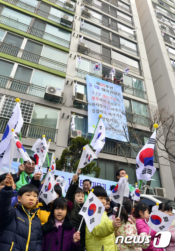 (서울=뉴스1) 최영호 기자 = 제95주년 3.1절을 앞두고 25일 오전 서울 성동구 사근동 중앙하이츠아파트에서 주민들과 아이들이 태극기를 흔들고 있다.성동구는 순국선열의 숭고한 …